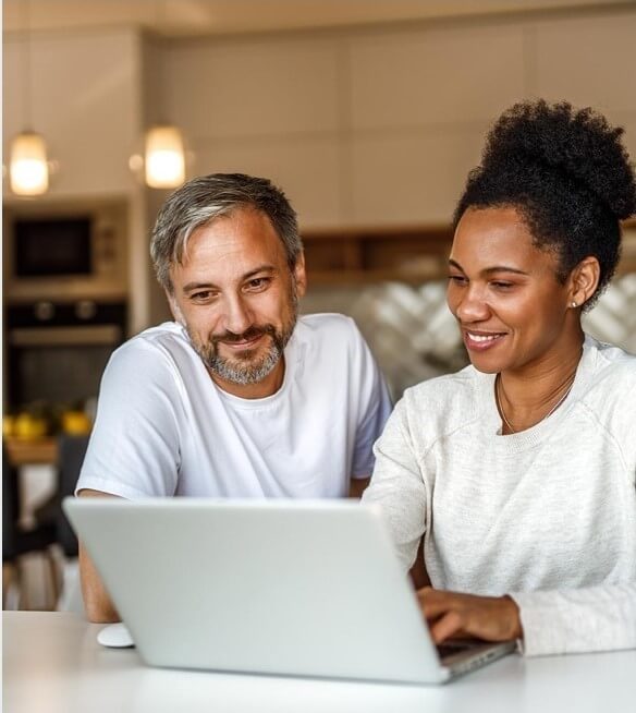 Man and woman sitting at a counter looking at a laptop