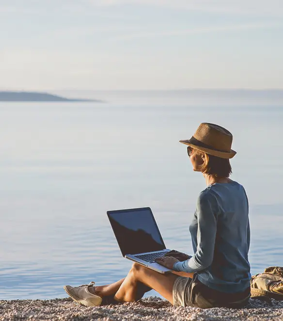  Woman sitting at water's edge with laptop